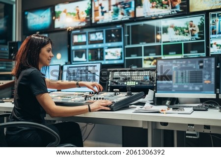 Young beautiful woman working in a broadcast control room on a tv station Royalty-Free Stock Photo #2061306392