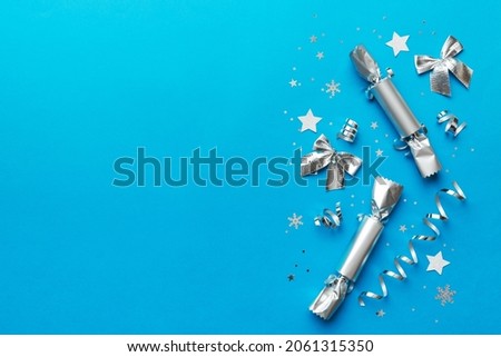 Christmas crackers with shiny confetti on color background, top view, copy space.