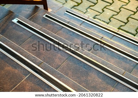 Closeup of ceramic tiles covering porch stairs with rubber anti slippery stripes on it. Royalty-Free Stock Photo #2061320822