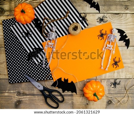 The concept of a happy Halloween holiday. Halloween decorations, bats, a skeleton on an orange background. Making jewelry. Handmade work.