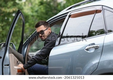 Handsome man getting out of modern car