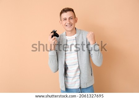 Happy young man playing video games on color background
