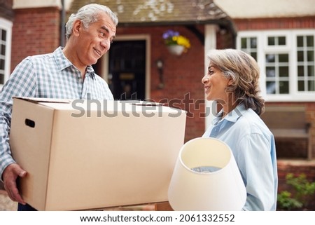 Portrait Of Mature Couple Carrying Boxes On Moving Day In Front Of Dream Home Royalty-Free Stock Photo #2061332552