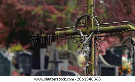 Graveyard Old Metal Crucifix Covered with Moss Coating with Christ Figure Standing among Graves on Public City Cemetery