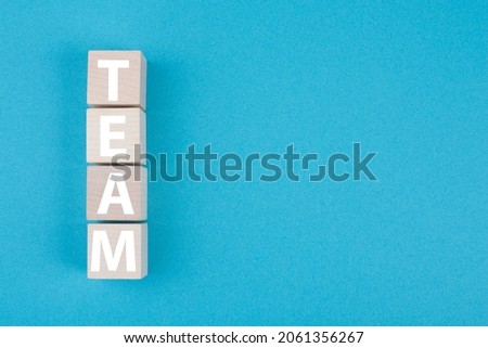 The word team is standing in white letters on wooden cubes, blue colored background, copy space
