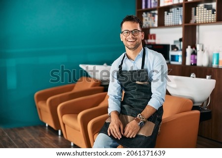 Young happy hairstylist working in a salon and looking at camera. Copy space. Royalty-Free Stock Photo #2061371639