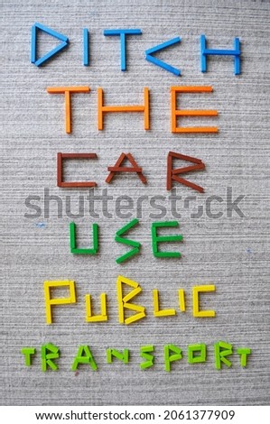 3D text in colour wooden bricks on wool carpet, which reads Ditch The Car Use Public Transport. Message for sustainability, climate change mitigation, climate action, carbon footprint reduction, CO2. Royalty-Free Stock Photo #2061377909