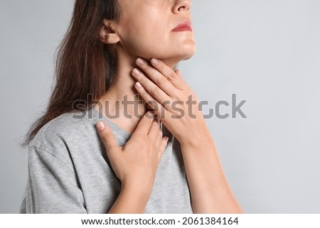 Mature woman doing thyroid self examination on light background, closeup Royalty-Free Stock Photo #2061384164