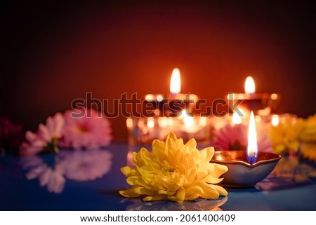 Happy Diwali. Traditional symbols of Indian festival of light. Burning diya oil lamps and flowers on red background. Copy space. Royalty-Free Stock Photo #2061400409