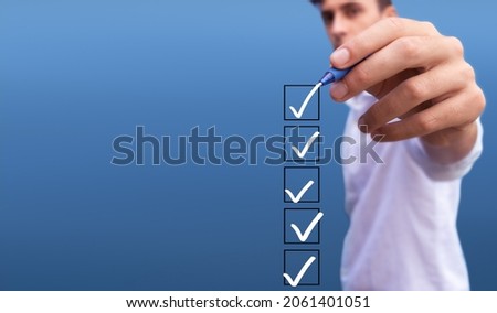Young man checking 5 boxes with list of options on blue background Royalty-Free Stock Photo #2061401051