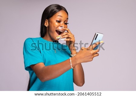 young black woman using her phone looking amazed