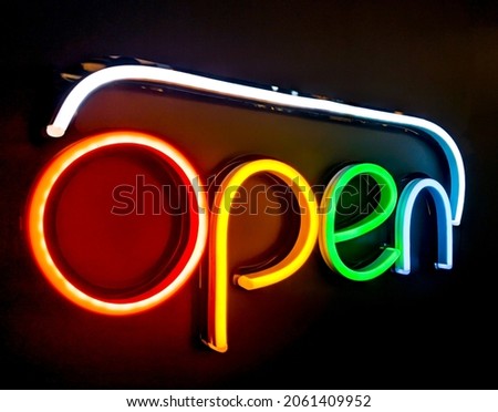 Bright electric neon red sign saying the word Open, indicating a store, shop, pub or restaurant is now open for business sign.