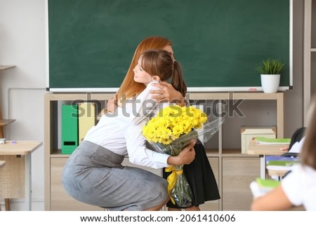 Little schoolgirl greeting her teacher in classroom Royalty-Free Stock Photo #2061410606