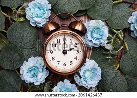 Alarm clock with eucalyptus leaves and flower decorate on wooden background