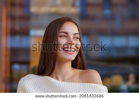 Emotional portrait of a beautiful happy smiling young woman with braces. Attractive girl bracket system posing in city outdoor. Brace, bracket, dental care, malocclusion, orthodontic health. Blurred Royalty-Free Stock Photo #2061432686
