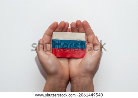 the flag of Russia, made of plasticine in the hands of a child on a white background Royalty-Free Stock Photo #2061449540