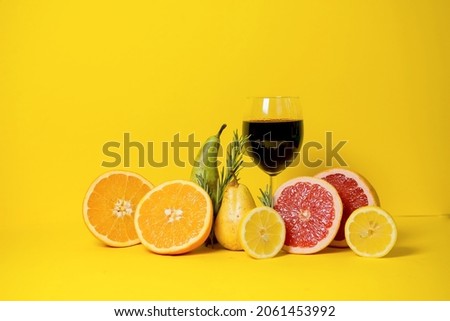 grapefruit, orange, lime and pearls on a yellow background with rosemary sprigs. And a glass of red wine. Advertising a party, a blog about vitamins and the benefits of red wine. copy space
