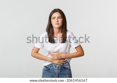 Woman having stomach ache, bending and holding hands on belly, discomfort from menstrual cramps Royalty-Free Stock Photo #2061456167
