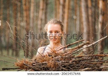 teenage girl with pimple skin collect branches firewood for a campfire while traveling through a summer forest in nature. young happy people survivalist traveler and local travel on great outdoors