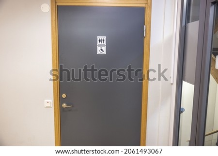 Close up view of gray door of public toilet with sign for men ,women with disability . Sweden. 