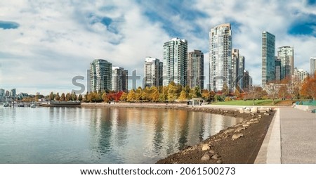 Scenic view of Downtown Vancouver on a sunny day. Beautiful fall panorama of modern waterfront cityscape with buildings, park and trees with red and yellow color. Selective focus.