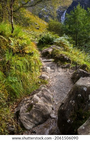 A hiking trail in the Nevis Gorge, with Steall Falls pictured in the distance, in the Highlands of Scotland.