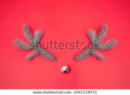 New year Christmas tree with silver disco ball. Deer face. Pastel red background. Minimal winter scene. Copy space.