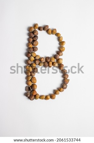 Autumn font letter B made of real natural hazelnuts against white paper background.Unique fall collection of letters. Top view. Flat lay.