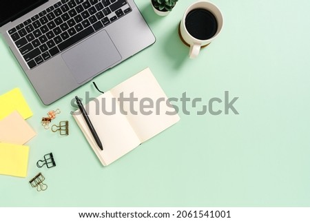 Creative flat lay photo of workspace desk. Top view office desk with laptop, coffee cup and open mockup black notebook on pastel green color background. Top view mock up with copy space photography.