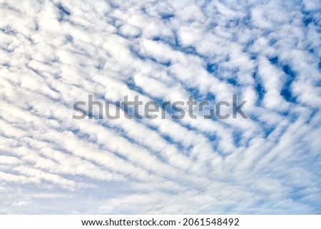 Beautiful blue sky with unusual white Altocumulus undulatus clouds, extraordinary cloud formation. White cirrocumulus clouds, altocumulus cloudy skies, stratocumulus cloud texture, blue sky background Royalty-Free Stock Photo #2061548492