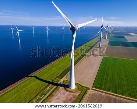 offshore windmill park with clouds and a blue sky, windmill park in the ocean aerial view with wind turbine Flevoland Netherlands Ijsselmeer. Green energy  Royalty-Free Stock Photo #2061562019