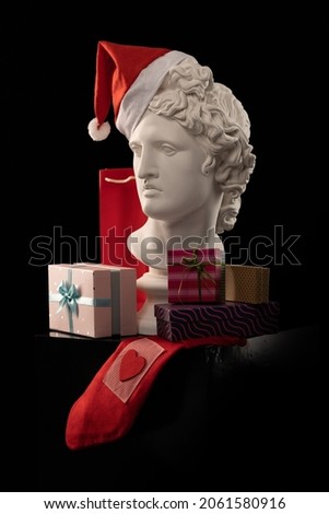 Design for postcards for Christmas and New Year. White plaster sculpture of a bust of Apollo in a red cap of Santa Claus