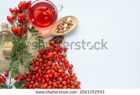 Dog rose, bunch branch Rosehips, types Rosa canina hips, essential oil and hot herbal tea cup on white background. Medicinal plants and herbs composition Royalty-Free Stock Photo #2061592943