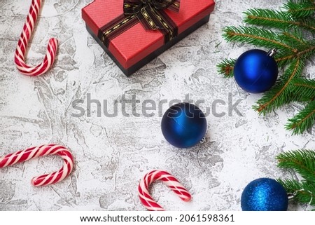New Year's or Christmas composition of spruce green branches, New Year's balls, gift and Christmas lollipops on a bright textural background. Flat lay, layout, frame, copy space
