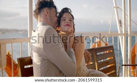 Newlyweds hug on background of cloudy sky. Action. Beautiful newlyweds happily cuddle in cloudy weather. Happy newlyweds in stylish outfits hug in windy weather Royalty-Free Stock Photo #2061599315