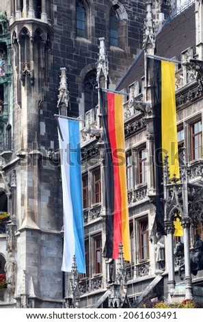 three large flags on the city hall of Munich symbolizing the colors of the city of the Region of Bavaria and of the nation Germany