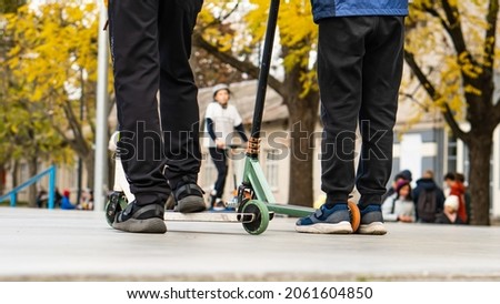 young boys ride on the sports field, on scooters and skates. street sports.
