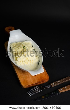 Singkong Thailand or called Thai sweet cassava serve with coconut milk and sprinkled with grated cheese on black background