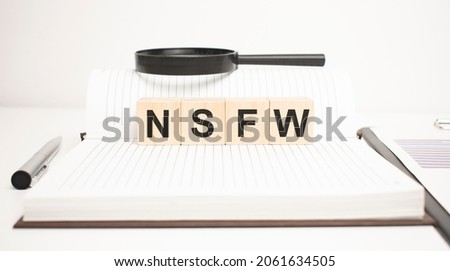 nsfw word concept. wooden cubes, notepad, pen and business charts. Royalty-Free Stock Photo #2061634505