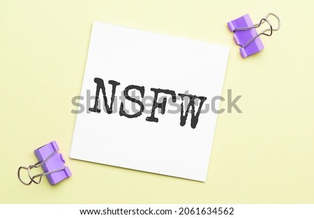 white paper with text nsfw on a yellow background with stationery Royalty-Free Stock Photo #2061634562