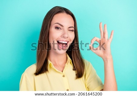 Photo of impressed millennial brunette lady show okey sign blink wear yellow blouse isolated on teal color background
