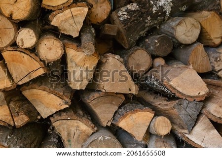 Chopped firewood, lot of logs with bark stacked up together, brown wooden backgrond.