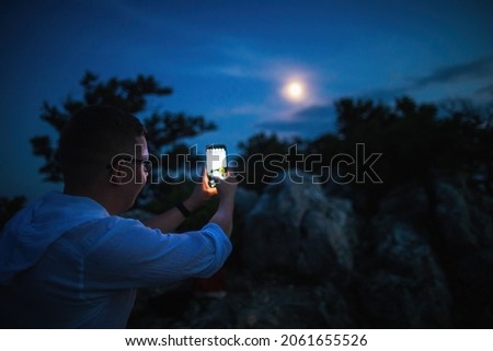 The concept of mobile astrophotography a young man photographs the moon on his phone