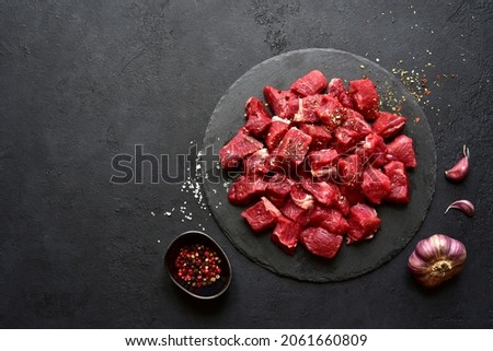 Raw organic meat ( beef or lamb ) on a black slate board. Top view with copy space. Royalty-Free Stock Photo #2061660809