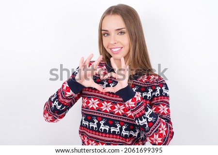 Serious Young caucasian girl wearing christmas sweaters on white background keeps hands crossed stands in thoughtful pose concentrated somewhere