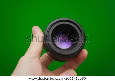 Lens 50 mm for the camera in hand on a green background. Accessories for the photographer.