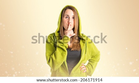 Young girl making silence gesture over ocher background 