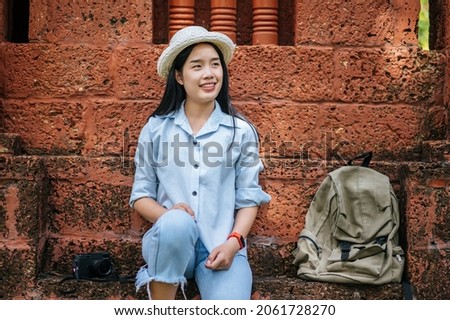 Portrait young backpacker female wearing hat traveling in ancient site, She use camera to taking photo with happiness, copy space
