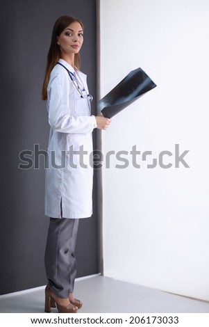 Female doctor with X-ray picture standing near grey wall