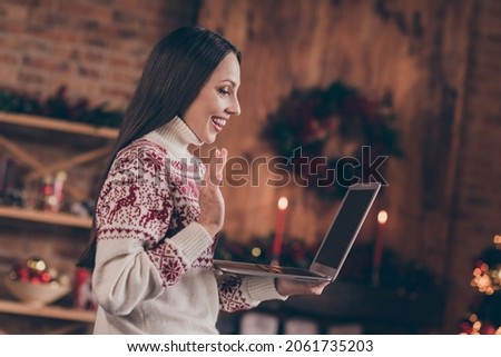 Photo of pretty funny young lady dressed print pullover talking modern device waving arm new year greetings smiling indoors room home house Royalty-Free Stock Photo #2061735203